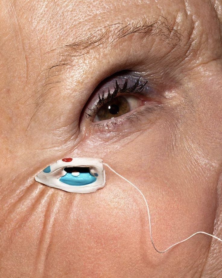 Extreme close-up of an eye with textured skin and a graphic ceramic accent