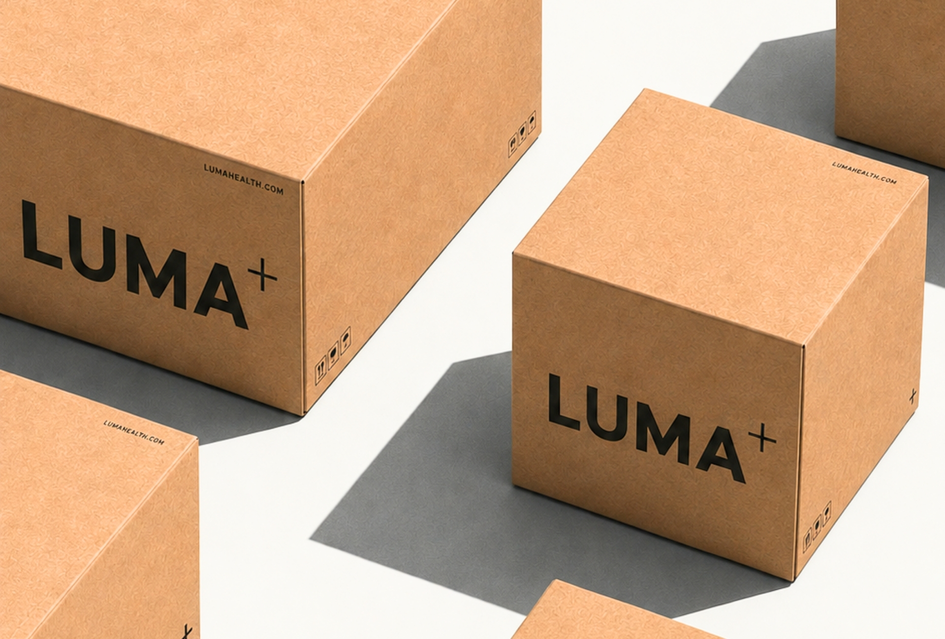 LUMA+ kraft shipping boxes arranged on a light background