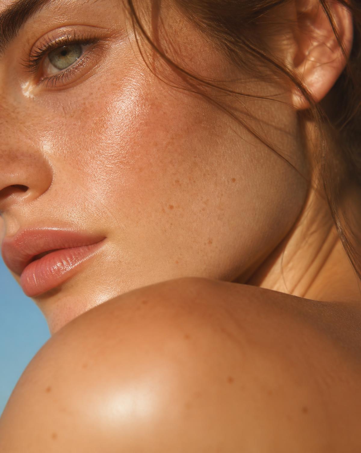 Macro beauty crop of dewy freckled skin in golden daylight